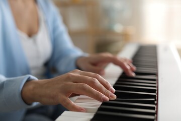 Woman playing synthesizer indoors, closeup. Electronic musical instrument
