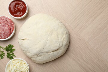 Making calzone pizza. Dough and ingredients on wooden table, flat lay. Space for text