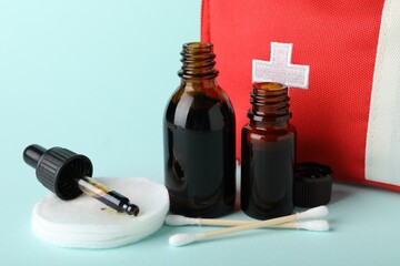 Topical iodine and other first aid kit components on light blue background