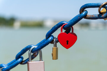 Red heart-shaped and other padlocks on a blue chain
