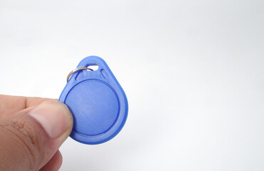 Fototapeta premium A blue RFID (Radio Frequency Identification) keychain receiver is held in a hand on a white background. Used by electronics, mechatronics, and networking engineers.