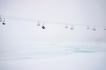 Ski chairlift above frozen lake in fog