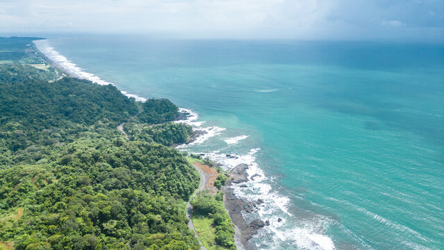Aerial shot of the turquoise beach and white waves on a sunny day in Jaco in Puntarenas of Costa Rica
