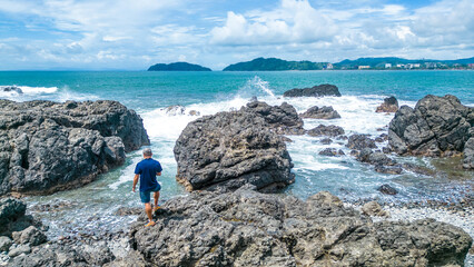 Tourist man contemplating the turquoise sea on a sunny day at the Jaco viewpoint in Puntarenas,...