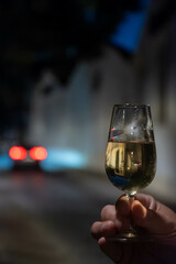 Hand with sherry wine glass with fino and old bogedas jerez wine cellars on background in Jerez de la Frontera, wine glasses outdoor, cityview, Andalusia, Spain
