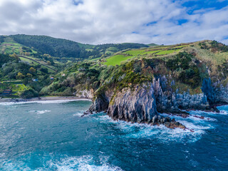 Fototapeta premium Praia dos Moinhos. Aerial drone view of volcanic black sand beach in Moinhos town, Sao Miguel, Azores, Portugal. Atlantic ocean coast