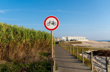 No bicycles allowed sign post on a beach front walkway in Aver-o-Mar, Portugal, on a bright sunny afternoon in autumn with blue sky.