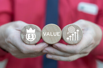 Business man holding wooden blocks sees word: VALUE. Increase value, growth value service, company...