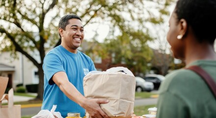Smiling man in blue shirt distributing food packages at outdoor event