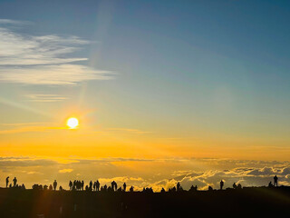 Obraz premium Sunrise over the mountain and above the clouds with silhouettes of people