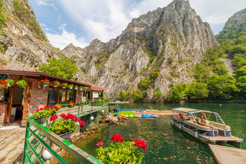 Tourists enjoying a scenic boat trip on the emerald waters of Matka Canyon, with restaurants and the church of Monastery of St. Andrea in Macedonia