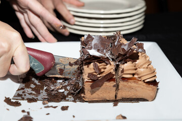 Un delicioso pastel de chocolate es cuidadosamente cortado, simbolizando el comienzo de un momento compartido y especial. La textura rica del chocolate y la disposición elegante resaltan el placer de 