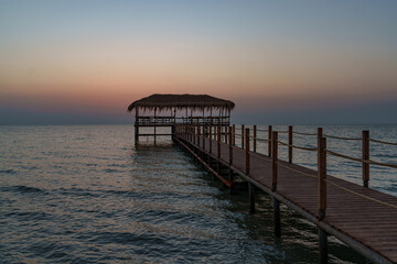 Fototapeta premium A beautiful view of the sunrise, sunset over the sea horizon with a pier in the foreground