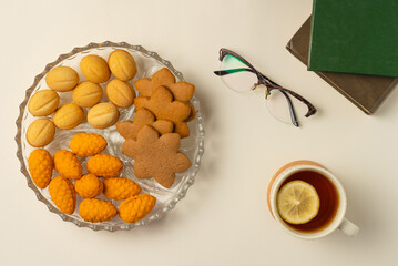 Coziness composition with cup of tea, cookies and books on beige background. Flat lay, top view.