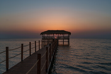 Obraz premium A beautiful view of the sunrise, sunset over the sea horizon with a pier in the foreground