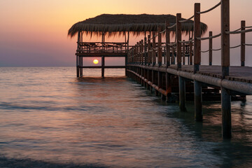 Obraz premium A beautiful view of the sunrise, sunset over the sea horizon with a pier in the foreground
