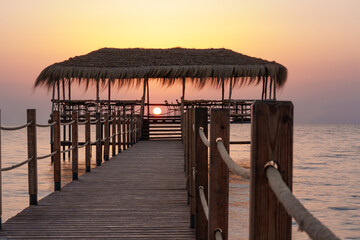 Obraz premium A beautiful view of the sunrise, sunset over the sea horizon with a pier in the foreground