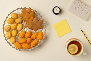 Blank sticker, plate with cookies, cup of tea, Christmas gift box on beige background. Flat lay, top view.