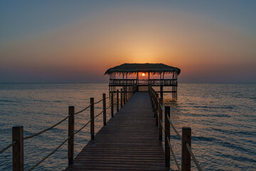 Obraz premium A beautiful view of the sunrise, sunset over the sea horizon with a pier in the foreground