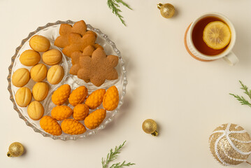 Plate with cookies, cup of tea and Christmas balls on beige background. Flat lay, top view.