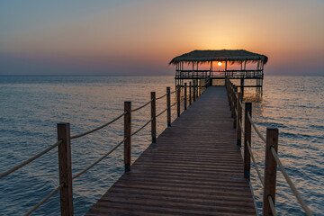 Obraz premium A beautiful view of the sunrise, sunset over the sea horizon with a pier in the foreground