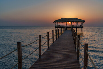 Fototapeta premium A beautiful view of the sunrise, sunset over the sea horizon with a pier in the foreground