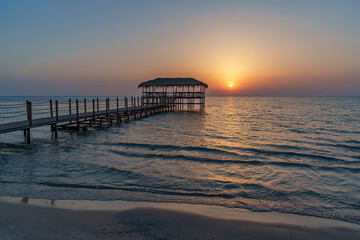 A beautiful view of the sunrise, sunset over the sea horizon with a pier in the foreground