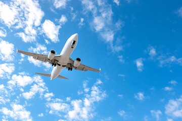 Obraz premium Airplane in flight against a vibrant blue sky with fluffy white clouds.