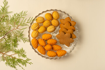 Plate with cookies and spruce branch on beige background. Flat lay, top view.