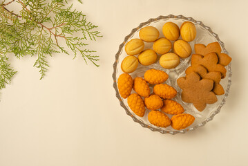 Plate with cookies and spruce branch on beige background. Flat lay, top view.