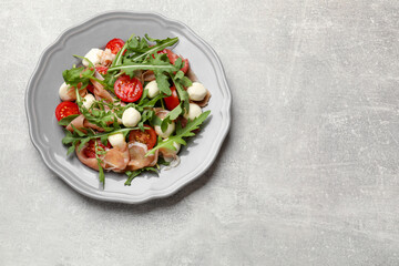 Tasty salad with arugula on grey textured table, top view. Space for text
