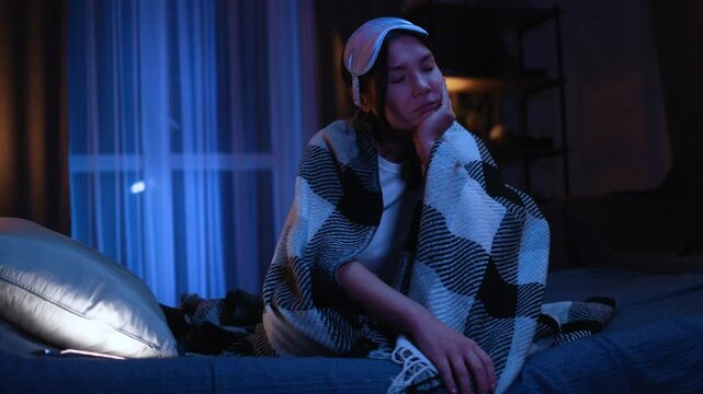 Tired asian woman with sleep bandage under the blanket feeling exhausted due to lack of sleep at night Depressed unhappy young female suffering from insomnia at bed