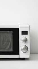 Fototapeta premium A sleek, modern microwave oven with a black glass door and simple control dials, set against a minimalist white wall.