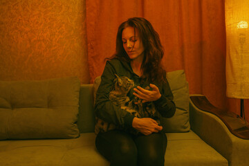 Young Woman Cuddling with Cat on Couch in Neon-Lit Room