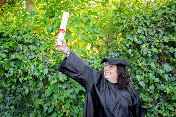 Woman recent graduated, dressed in cap and gown, showing off her degree celebrating.
