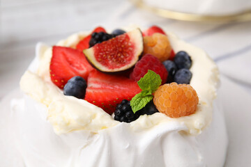 Pavlova cake (meringue dessert) with whipped cream, fresh berries, fig and mint on table, closeup