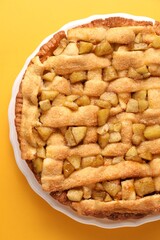 Tasty homemade apple pie on yellow background, top view