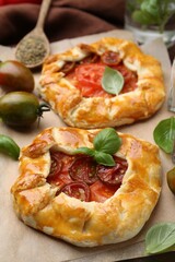 Tasty galettes with tomato and basil on table, closeup