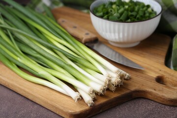 Fresh green onions on brown table, closeup