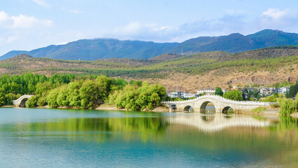 Lijiang Qingxi Reservoir offers a serene retreat with crystal-clear waters reflecting the surrounding mountains, creating a picturesque and tranquil landscape.