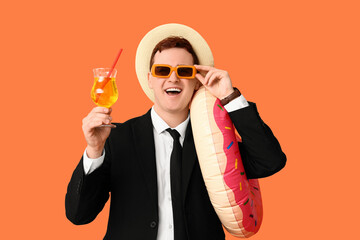 Office worker with inflatable ring and cocktail dreaming about vacation on orange background