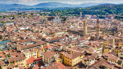 Fototapeta premium A bird's-eye view of Florence, italy reveals a breathtaking panorama of the city's iconic red-tiled rooftops, the majestic Duomo, and the Arno River, all framed by the rolling Tuscan hills.
