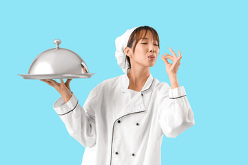Female Asian chef with cloche on blue background
