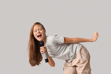 Cute girl singing with modern microphone on grey background