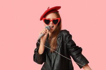 Cute girl with singing modern microphone on pink background