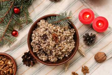 Bowl of traditional Ukrainian Kutya dish with Christmas tree branches and burning candles on white background