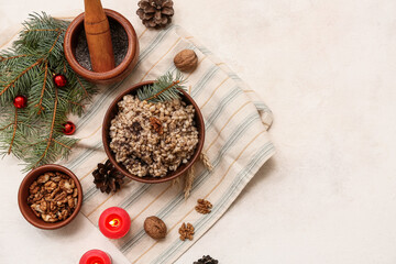 Bowl of traditional Ukrainian Kutya dish with Christmas tree branches and burning candles on white background