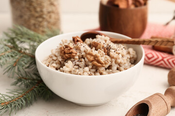 Bowl of traditional Ukrainian Kutya dish and Christmas tree branch on white table