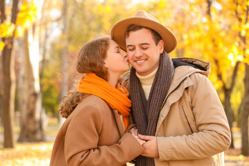 Beautiful loving young happy couple kissing in autumn park