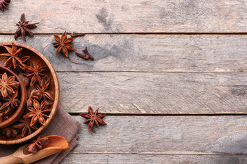 Bowls with aromatic star anise and scoop on wooden background